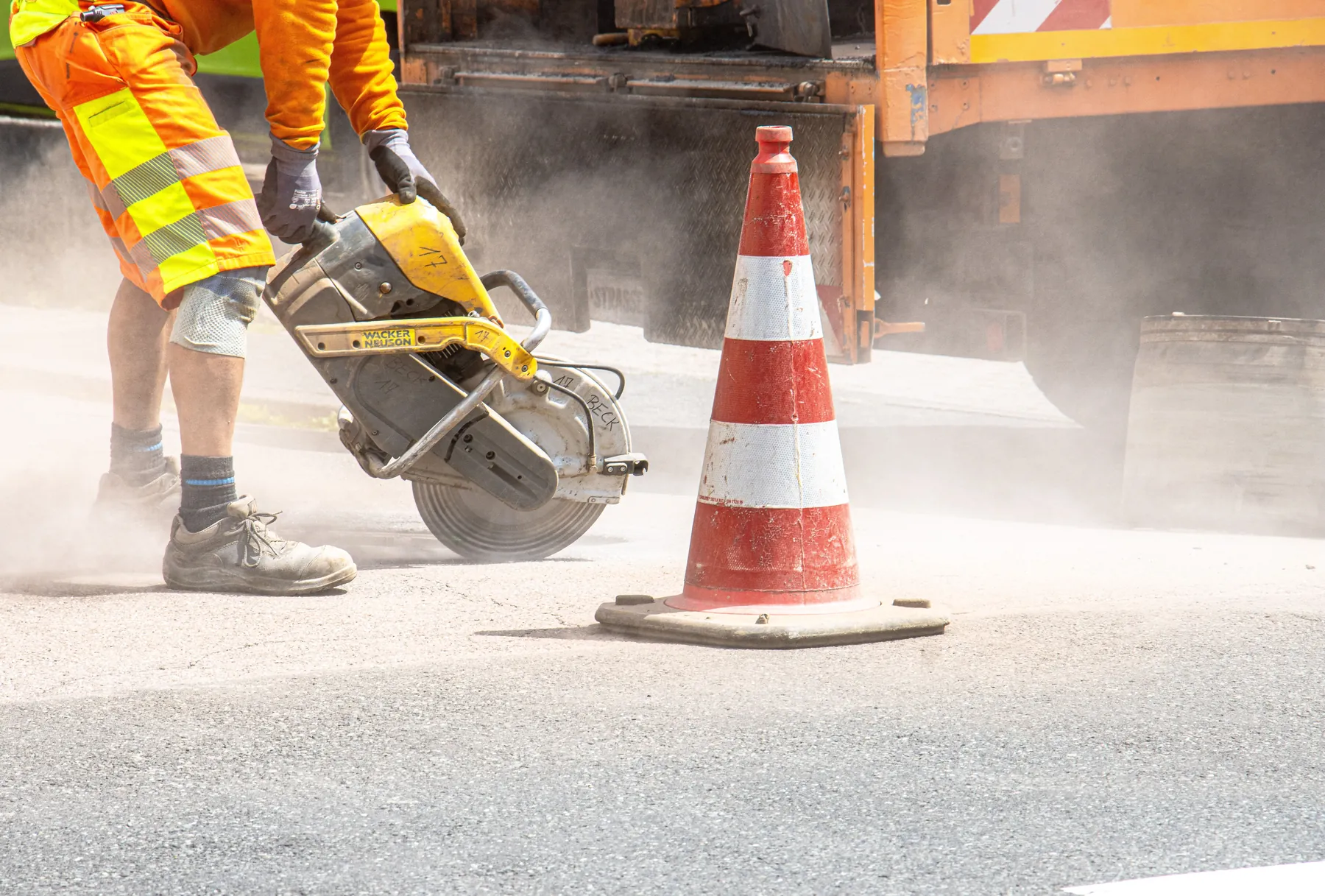Road construction worker cutting pavement